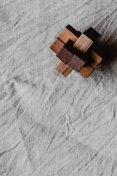 A minimalist wooden brain game placed on a textured textile background.