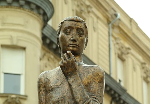 A detailed bronze statue in front of a historic building in Győr, Hungary, showcasing classic architecture.
