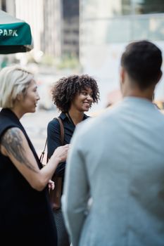 Group of coworkers chatting happily on a city street during a break.
