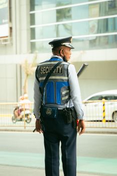 Security guard in uniform standing outdoors on a city street, maintaining public safety.