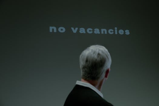 Senior man facing a 'No Vacancies' sign symbolizing job search challenges and ageism.